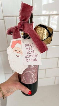 someone holding up a wine bottle with some stickers on it and a santa hat