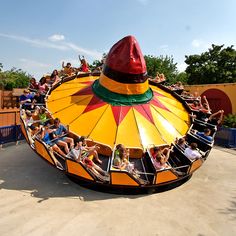 several people are riding on a ride at an amusement park in the day time,