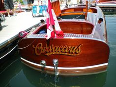 several small wooden boats docked at a pier with people walking around the dock area in the background