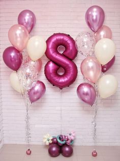 balloons and streamers are arranged in the shape of the number eight on a wall