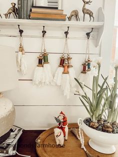 a wooden table topped with a potted plant next to a shelf filled with spools of thread