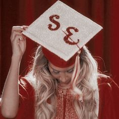 a woman wearing a graduation cap with the number 33 on it's side and she is holding her hair in front of her head