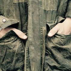 a person with their hands in the pockets of an army jacket that is partially open