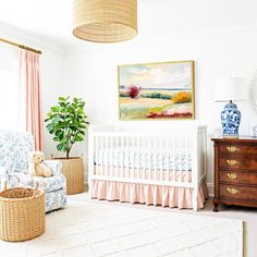 a baby's room with a crib, chair and painting on the wall