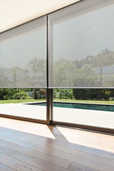 an open window with blinds on it in front of a pool and large glass doors