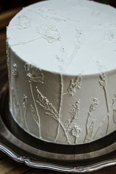 a white frosted cake sitting on top of a wooden table