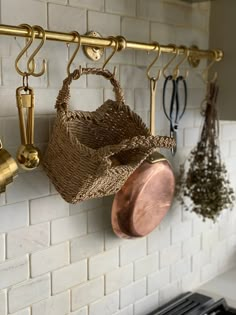 pots and pans hanging from hooks on a brick wall in a kitchen with an oven