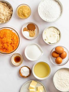 an assortment of ingredients in bowls on a white counter top, including eggs, cheese and flour