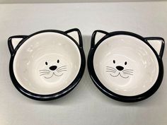 two black and white cat bowls with faces on them