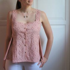 a woman standing in front of a white wall with her hands on her hips and looking at the camera