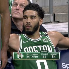 a man in a boston basketball uniform sitting on the bench