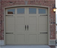 an image of a garage door in front of a brick building with two lights on the side