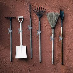 four different types of garden tools hanging on a red wall with snow flakes and rakes