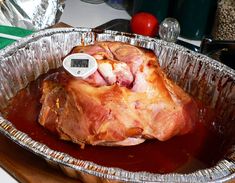 a large piece of meat sitting in a tin pan on top of a wooden cutting board