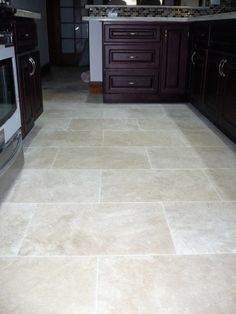 a kitchen with dark wood cabinets and tile flooring