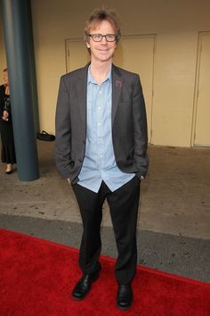 a man standing on a red carpet in a suit