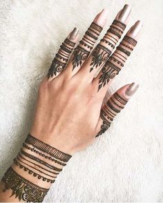 a woman's hands with hennap tattoos on their fingers and wristbands