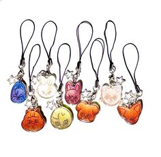 six different colored glass charms with cats and hearts on each one, hanging from a black cord