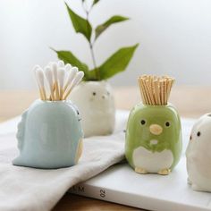 three ceramic birds with toothpicks in their beaks sitting on a white towel