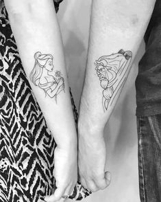 two people holding hands with disney tattoos on their arms and wrist, both wearing matching outfits