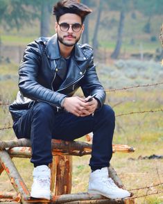 a man sitting on top of a wooden bench next to a barbed - wire fence