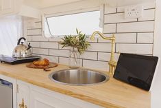 a kitchen counter with a laptop on it and a potted plant next to the sink