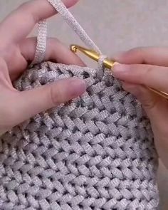 someone crocheting the ends of a purse with gold scissors