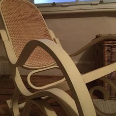 a wicker rocking chair sitting in front of a window