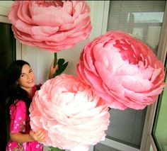 a woman is holding three large pink flowers