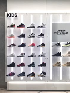 a display case filled with lots of different types of shoes in front of a white wall