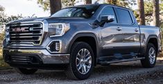 a silver gmc sierra is parked in the woods