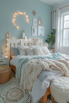 a bedroom with blue walls, white bedding and lights on the windowsills