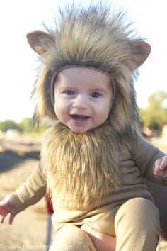 a baby in a lion costume sitting on the ground