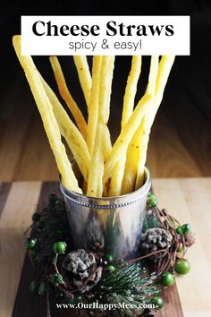 french fries are in a metal cup on a wooden table next to pine cones and berries