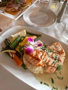 a white plate topped with meat and veggies next to a glass of water