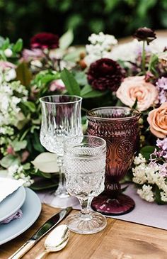 the table is set with wine glasses and flowers