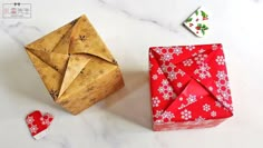 an origami box next to a folded piece of paper on a marble surface