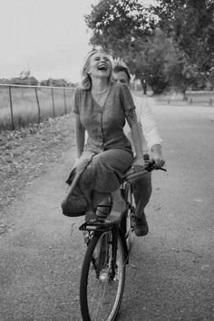 a man and woman riding on the back of a bike