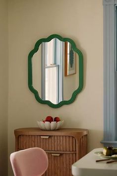 a mirror on the wall above a dresser with a bowl of fruit in front of it