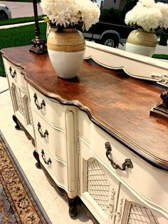 an old dresser with flowers in a vase sitting on it's top and mirror behind it