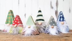 small christmas trees are lined up on a wooden surface with white and green decorations around them