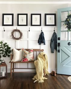 a wooden bench sitting in front of a white wall with pictures hanging on it's side