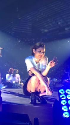 a woman sitting on top of a stage with her legs crossed in front of her