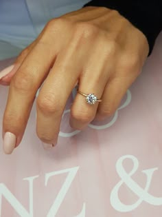 a close up of a person's hand with a diamond ring on their finger