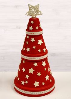 a red and white christmas tree with gold stars on it's top is shown