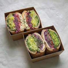 two open sandwiches sitting in a box on top of a white tablecloth covered floor