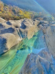 a rainbow colored river in the mountains with rocks and grass on either side that is blue