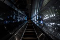 an escalator in a subway station with graffiti on the walls and stairs leading up to it