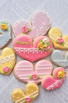 decorated heart shaped cookies with the words merci written on one side and roses in the other