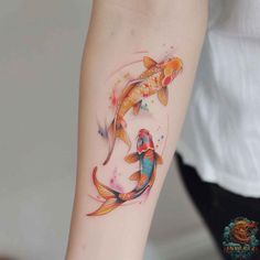 a woman's arm with two koi fish tattoos on it